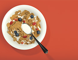 A bowl of cereal with a spoon seen from above.