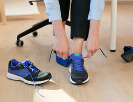A woman swaps heels for walking shoes in an office setting.