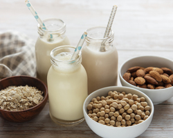 Three glass containers of milk sit near small bowls of rice, soybeans and oats.