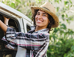 A woman in a straw hat leans out of a van.