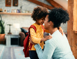 Child with backpack smiling with mother